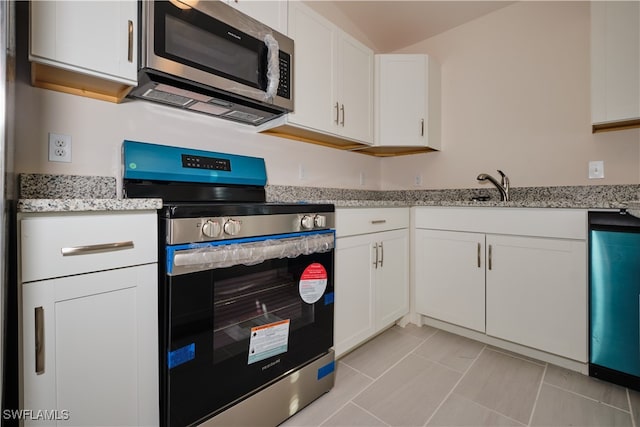 kitchen with light tile patterned floors, light stone counters, white cabinetry, and appliances with stainless steel finishes