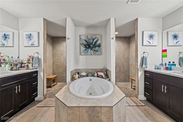 bathroom with plus walk in shower, vanity, and wood-type flooring