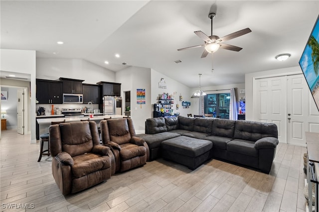 living room with ceiling fan with notable chandelier, light hardwood / wood-style floors, and vaulted ceiling