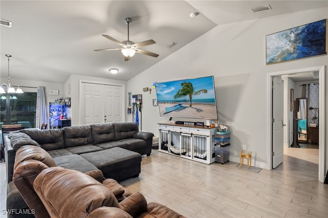 living room with ceiling fan with notable chandelier, light wood-type flooring, and lofted ceiling