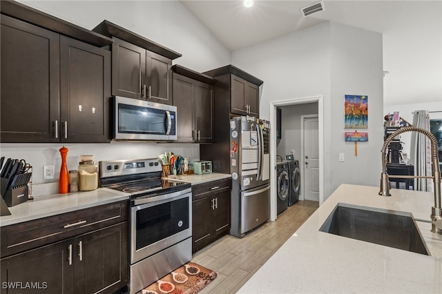 kitchen featuring high vaulted ceiling, sink, separate washer and dryer, light hardwood / wood-style floors, and stainless steel appliances