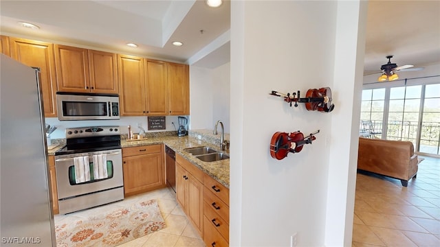 kitchen featuring sink, ceiling fan, light tile patterned floors, appliances with stainless steel finishes, and light stone counters