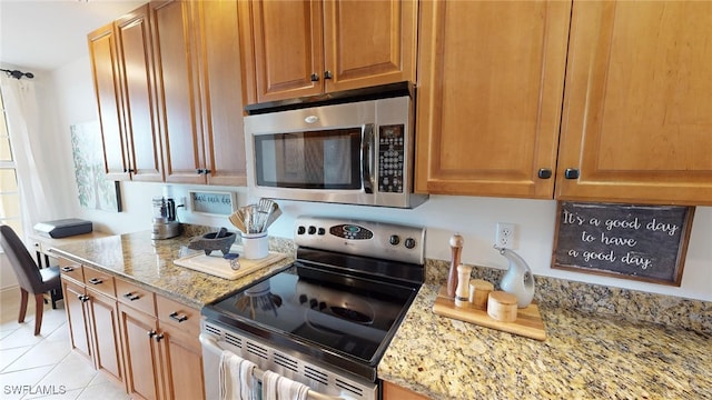 kitchen featuring light stone countertops, light tile patterned floors, and appliances with stainless steel finishes