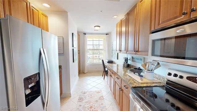 kitchen featuring light stone counters, light tile patterned flooring, and stainless steel appliances