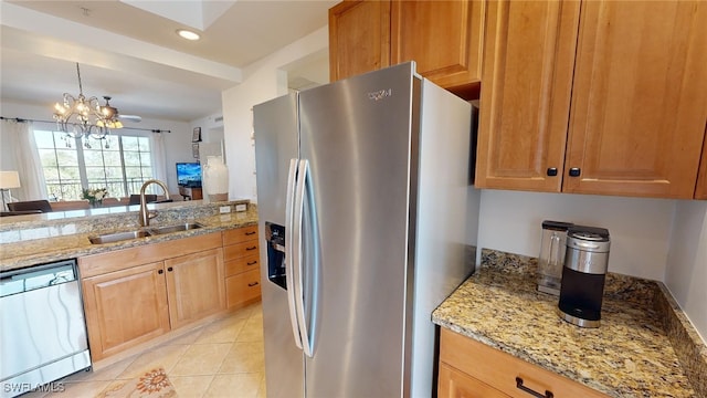 kitchen with an inviting chandelier, sink, light stone countertops, appliances with stainless steel finishes, and light tile patterned flooring