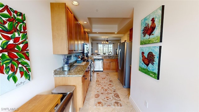 kitchen with sink, an inviting chandelier, light stone counters, light tile patterned floors, and appliances with stainless steel finishes