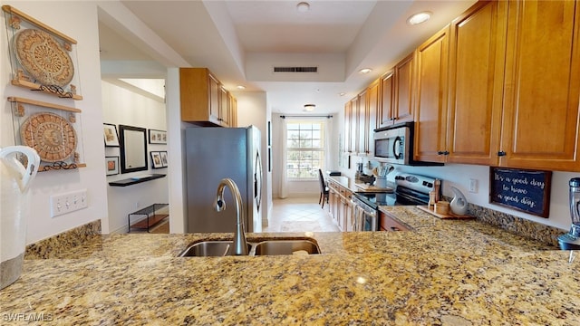 kitchen featuring kitchen peninsula, light stone counters, stainless steel appliances, sink, and light tile patterned flooring