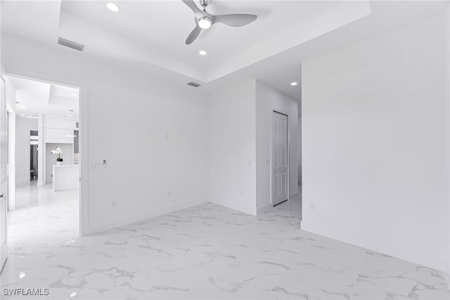 empty room featuring ceiling fan and a tray ceiling