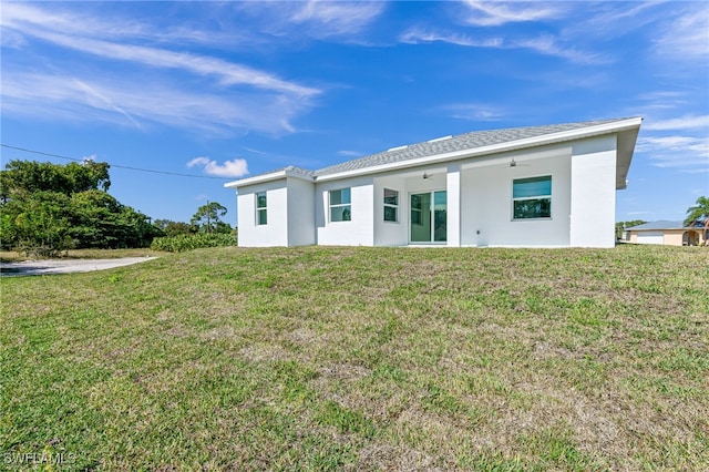 rear view of property with ceiling fan and a yard