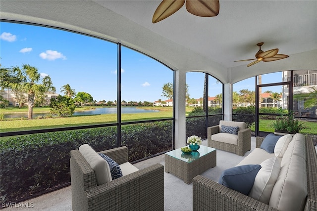 sunroom with ceiling fan and a water view