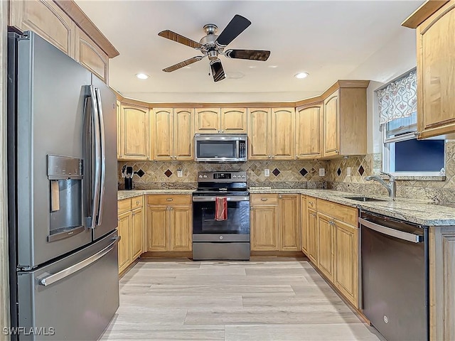 kitchen featuring sink, decorative backsplash, light hardwood / wood-style floors, light stone counters, and stainless steel appliances