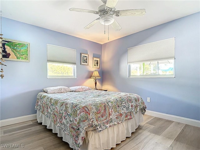 bedroom with hardwood / wood-style flooring, ceiling fan, and multiple windows