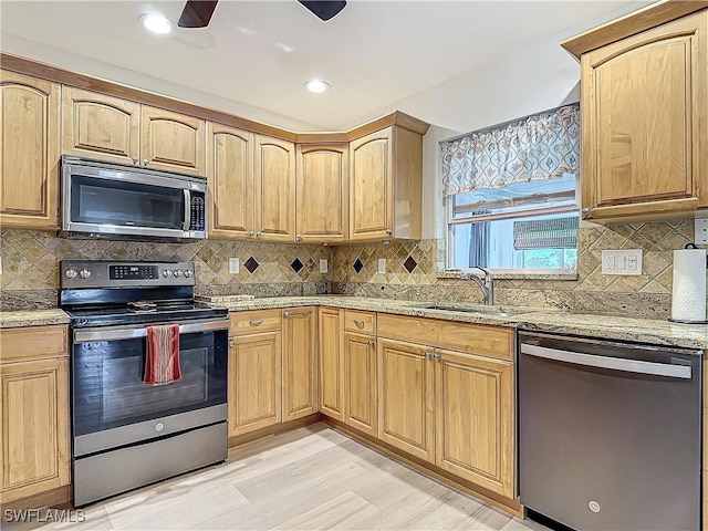 kitchen featuring backsplash, sink, light stone countertops, and stainless steel appliances