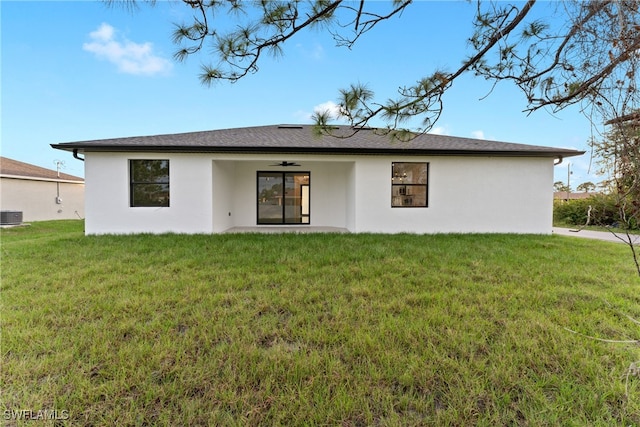 back of property with a yard and central AC