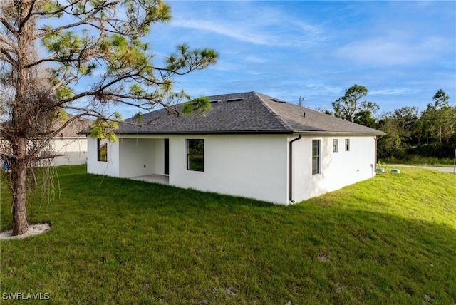 rear view of house featuring a lawn and a patio