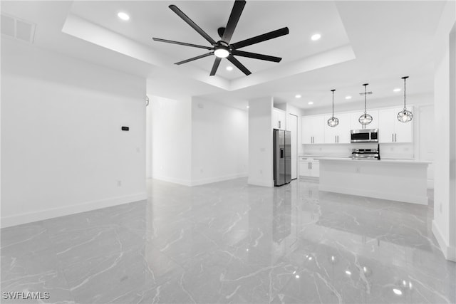 unfurnished living room with a tray ceiling and ceiling fan