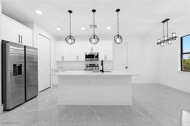 kitchen featuring a center island with sink, pendant lighting, white cabinetry, and appliances with stainless steel finishes