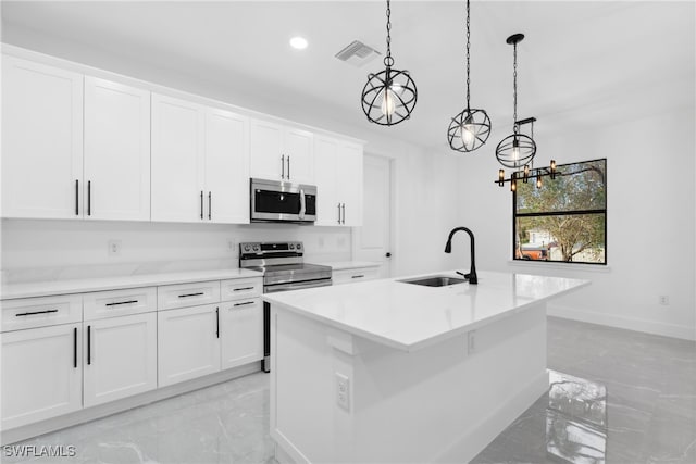 kitchen featuring pendant lighting, white cabinetry, a kitchen island with sink, and appliances with stainless steel finishes