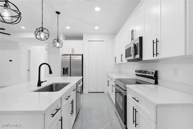 kitchen featuring appliances with stainless steel finishes, sink, decorative light fixtures, white cabinets, and an island with sink