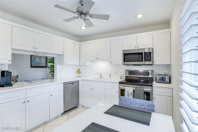 kitchen featuring appliances with stainless steel finishes, light tile patterned floors, tasteful backsplash, and white cabinetry