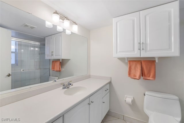 bathroom featuring tile patterned flooring, vanity, toilet, and a shower with shower door