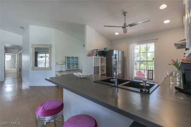 kitchen featuring ceiling fan, sink, stainless steel fridge, hardwood / wood-style floors, and lofted ceiling