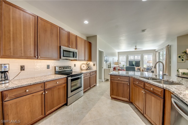 kitchen with sink, ceiling fan, light stone countertops, tasteful backsplash, and stainless steel appliances