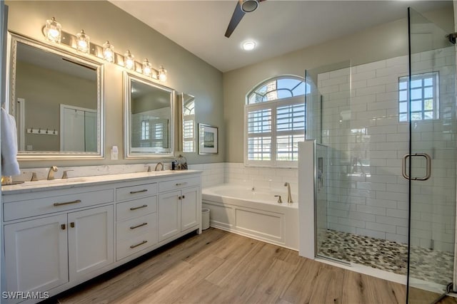 bathroom featuring a sink, double vanity, a stall shower, wood finished floors, and a garden tub