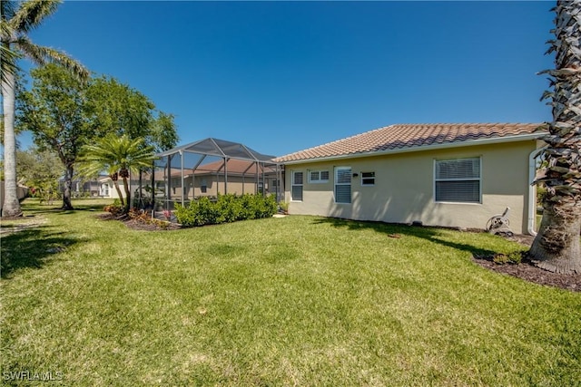 rear view of property featuring stucco siding, a tile roof, a lanai, and a yard