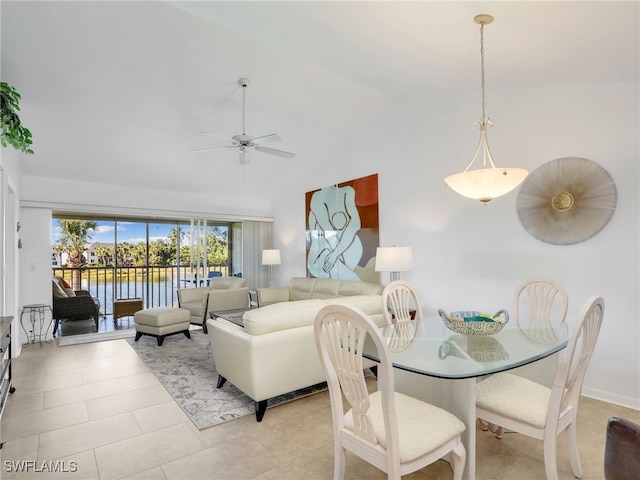 tiled dining space featuring ceiling fan, a water view, and lofted ceiling