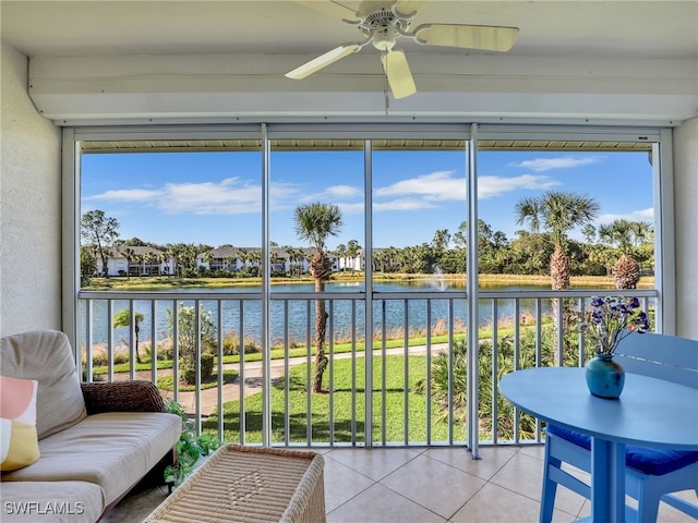 sunroom featuring ceiling fan and a water view