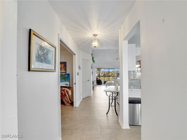 hall featuring light tile patterned floors and a textured ceiling