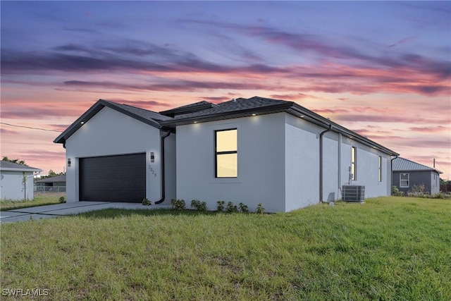7029 Palpano Cir, Labelle, FL 33935 - property exterior at dusk featuring stucco siding, cooling unit, an attached garage, and driveway