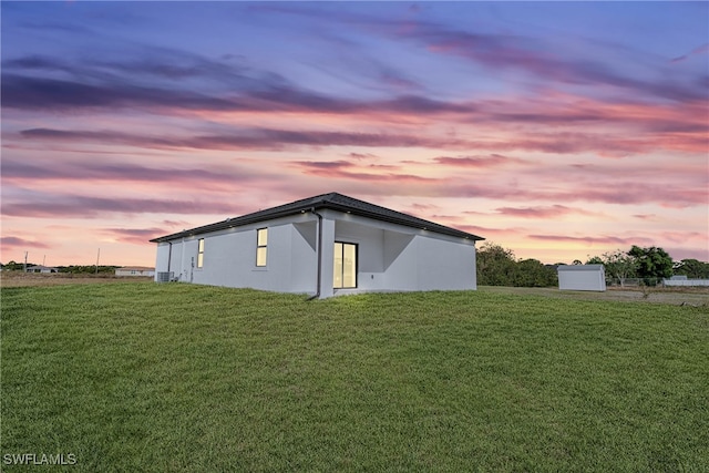 property exterior at dusk featuring a yard