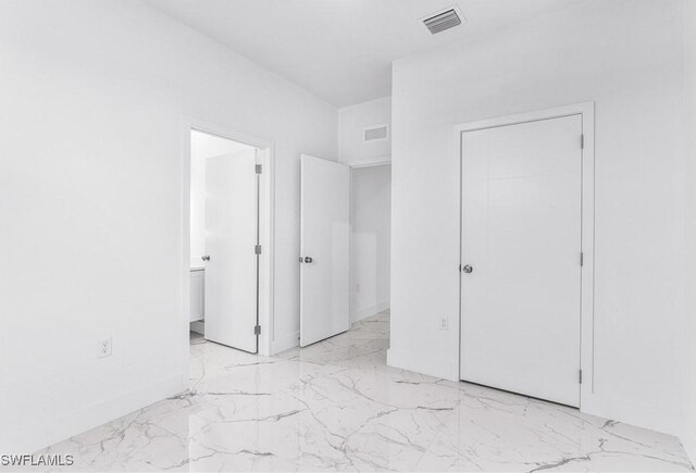 7029 Palpano Cir, Labelle, FL 33935 - unfurnished bedroom featuring light marble finish floors, baseboards, and ensuite bath