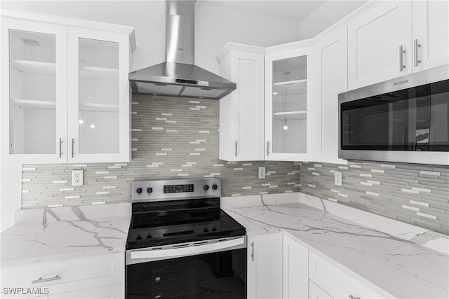 kitchen with decorative backsplash, stainless steel appliances, white cabinetry, and wall chimney range hood