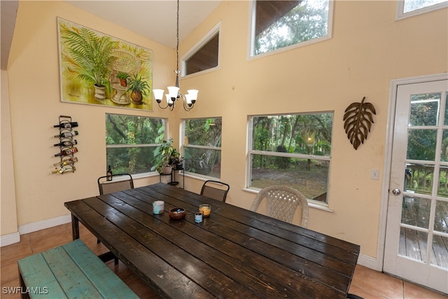 dining area featuring tile patterned flooring, high vaulted ceiling, a healthy amount of sunlight, and an inviting chandelier