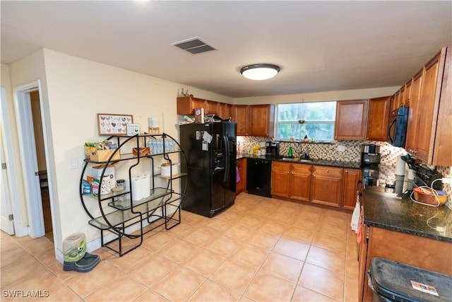 kitchen featuring sink, tasteful backsplash, dark stone countertops, and black appliances