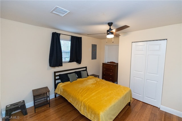 bedroom featuring ceiling fan, dark hardwood / wood-style floors, electric panel, and a closet