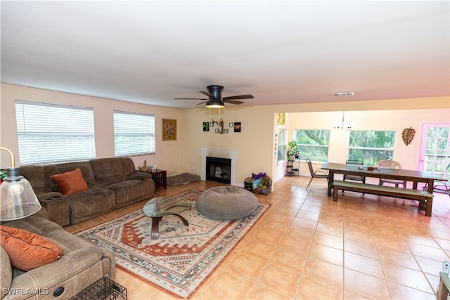 tiled living room featuring ceiling fan with notable chandelier