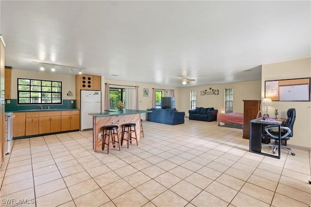 tiled dining space with ceiling fan and sink