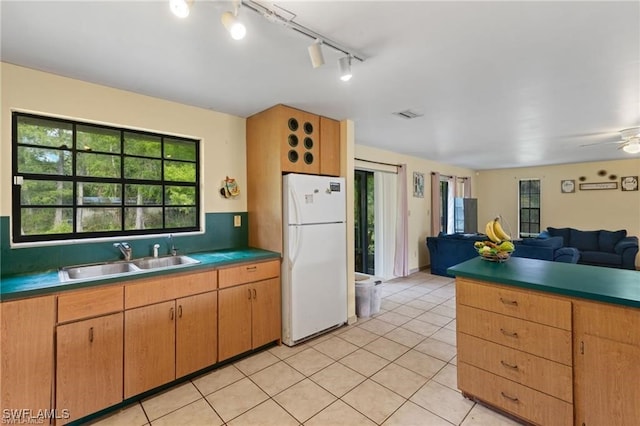 kitchen with ceiling fan, sink, rail lighting, white fridge, and light tile patterned floors