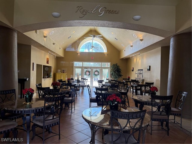 tiled dining room with a textured ceiling, high vaulted ceiling, and ceiling fan