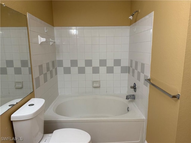 bathroom with tiled shower / bath combo and toilet