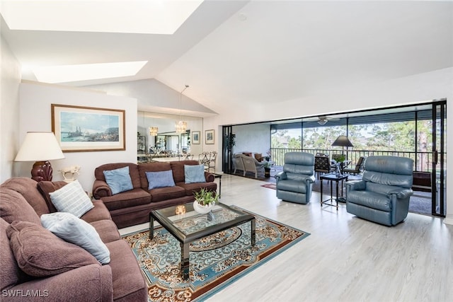 living room featuring wood-type flooring, an inviting chandelier, and lofted ceiling with skylight