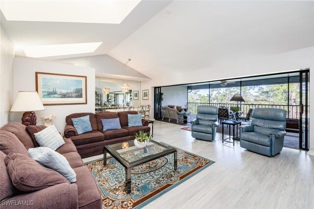 living area featuring a skylight, lofted ceiling, wood finished floors, and a chandelier