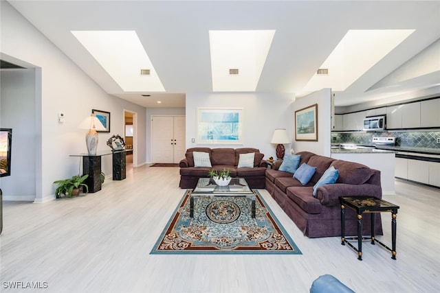 living room featuring light hardwood / wood-style floors and a skylight