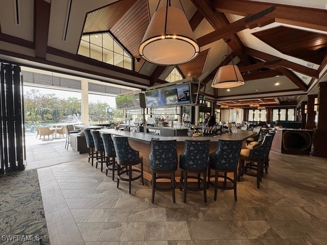 bar featuring decorative light fixtures, beam ceiling, and high vaulted ceiling