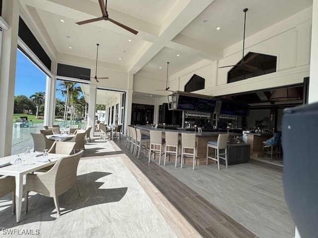 interior space featuring beam ceiling, a towering ceiling, and ceiling fan