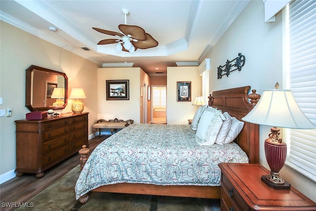 bedroom with ensuite bath, dark hardwood / wood-style floors, ceiling fan, ornamental molding, and a tray ceiling